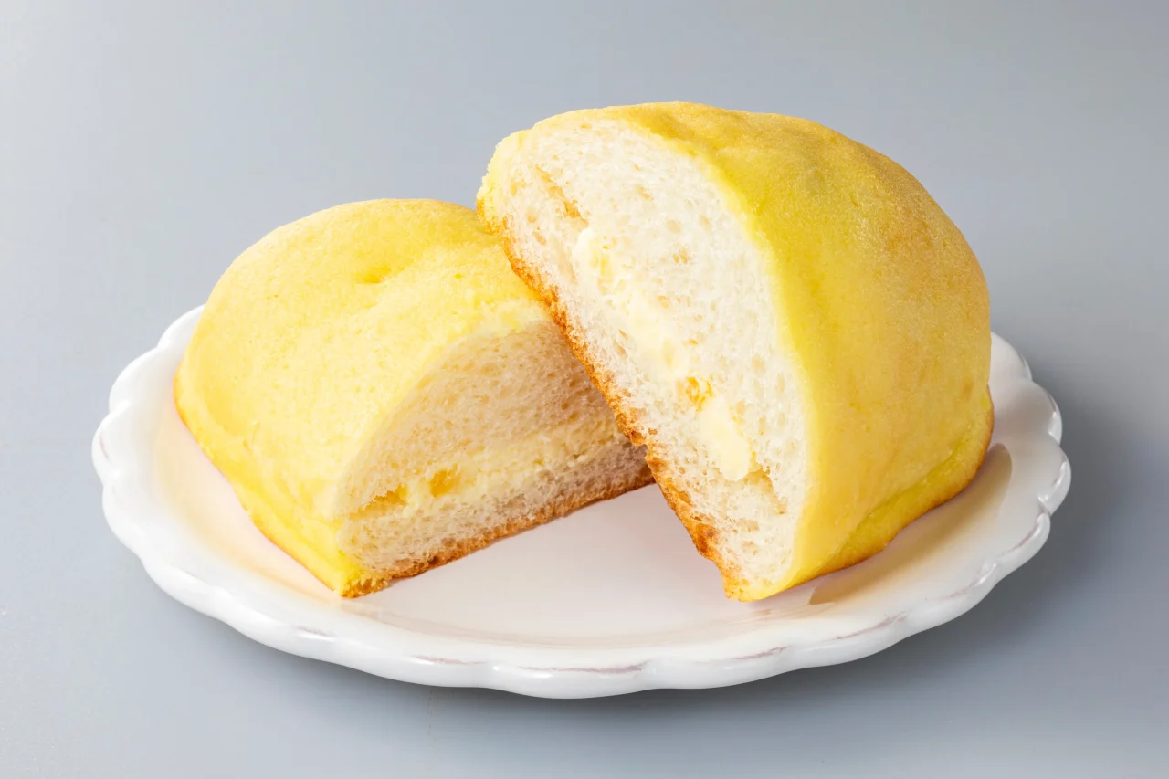 白い皿に半分に切ったクリーム入りの黄色いパン
