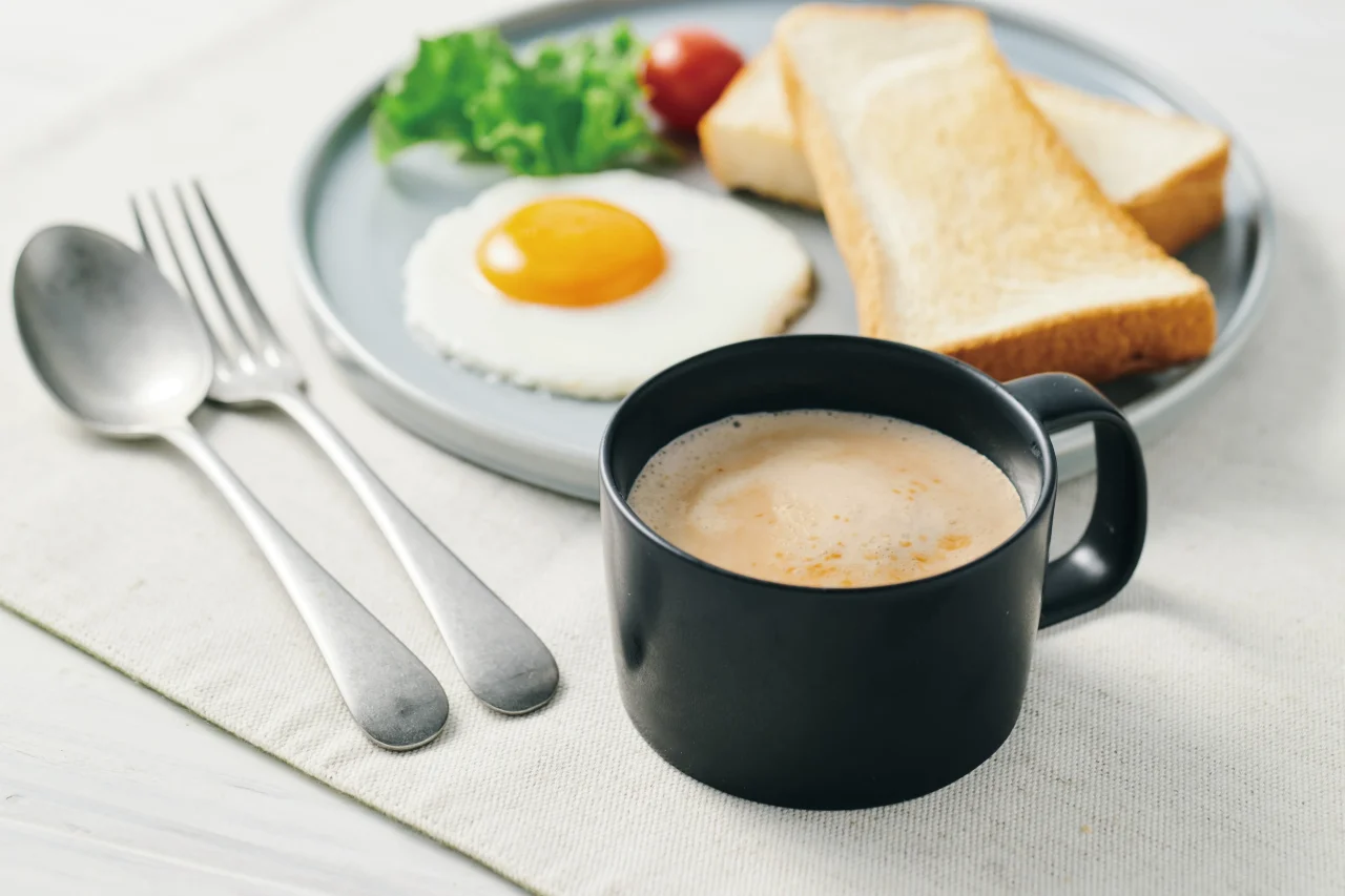 黒いマグカップのラテと目玉焼き、トーストの朝食プレート