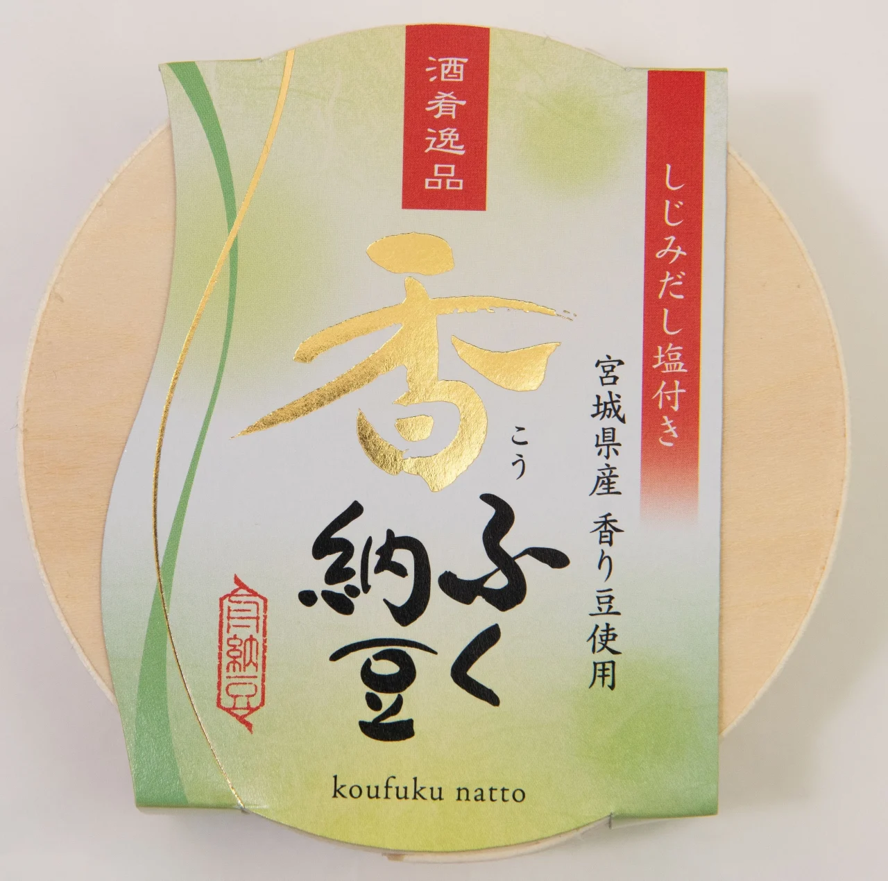 香ふく納豆のパッケージ。丸い木製容器に緑の帯と金文字の紙帯