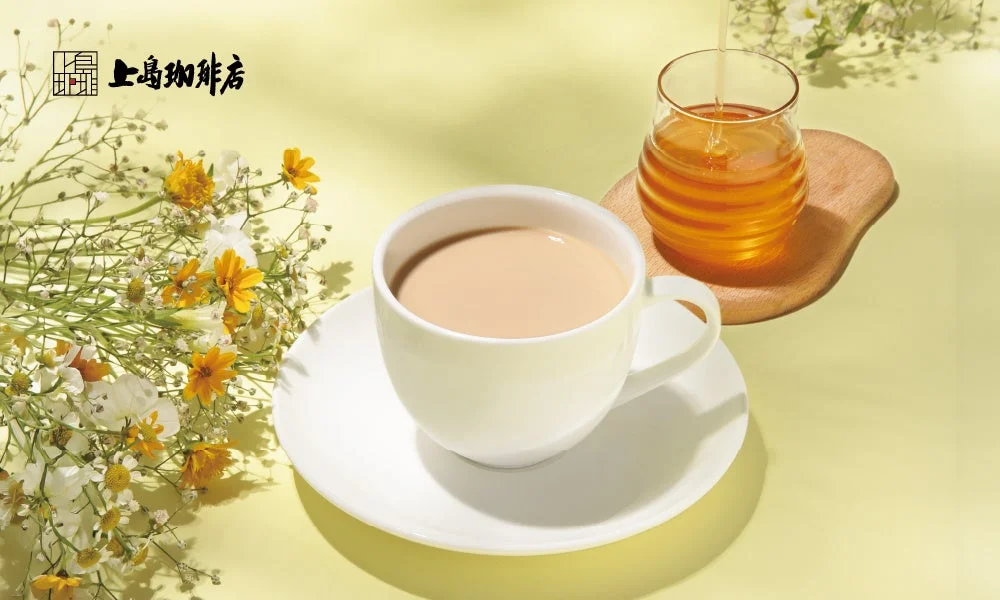 日本蜜蜂のはちみつミルク珈琲。白いカップと別添えのはちみつ、花