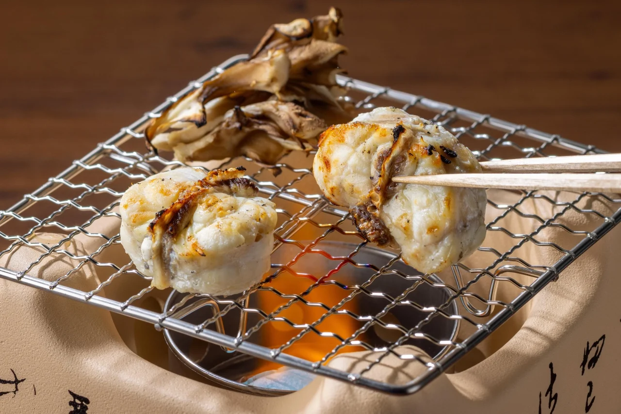 北海道産 真ふぐの網焼き。焼き網で炙られた白身と舞茸風のきのこ