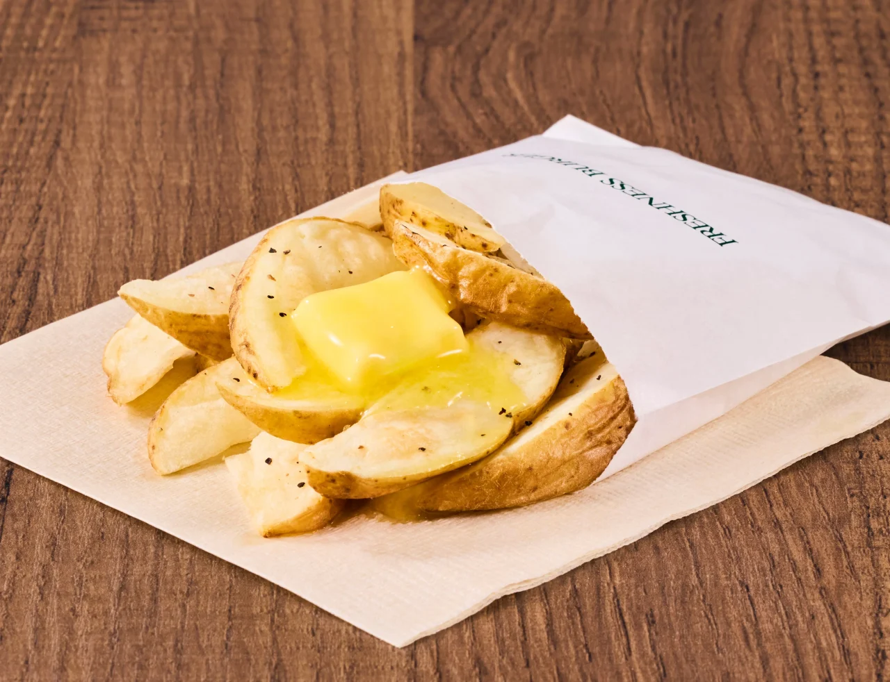 北海道産じゃがバター（トヨシロ）。紙袋に入った皮付きポテトにバターをのせた様子