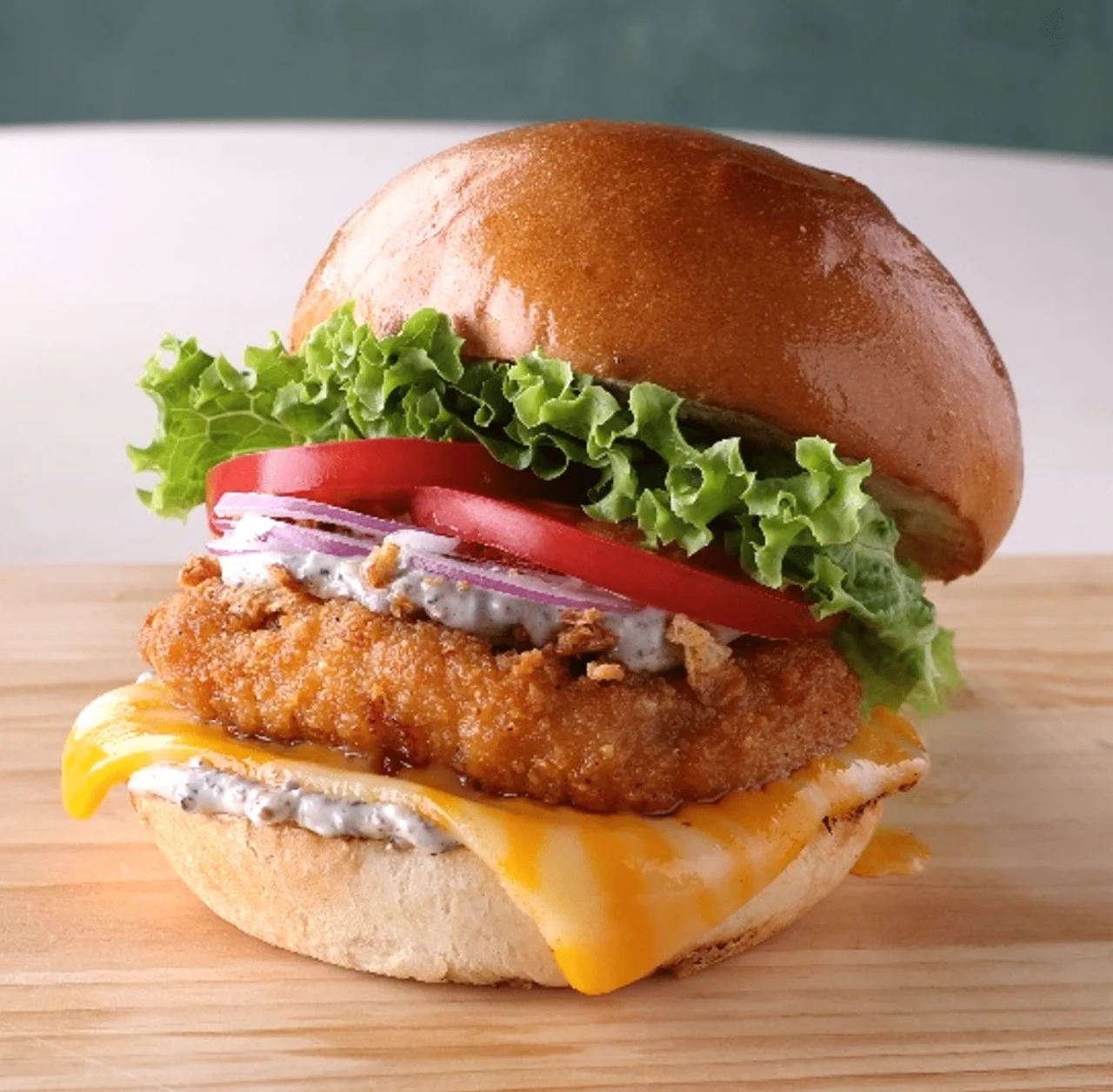 トリュフ コルビージャック チキンバーガー。フライドチキンとチーズ、レタス、トマト入り