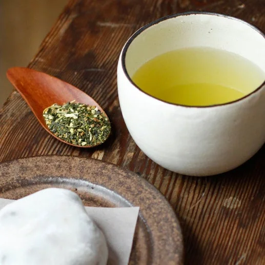 柚子緑茶のイメージ。白い湯のみの緑茶と木のさじにのせた茶葉