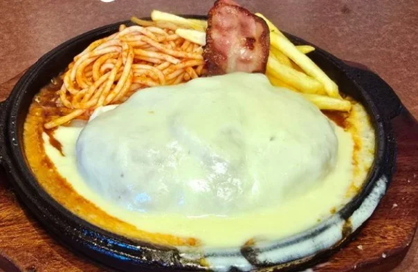 背徳のやりすぎチーズハンバーグ。チーズがかかり、ベーコンとポテト、スパゲッティが付く