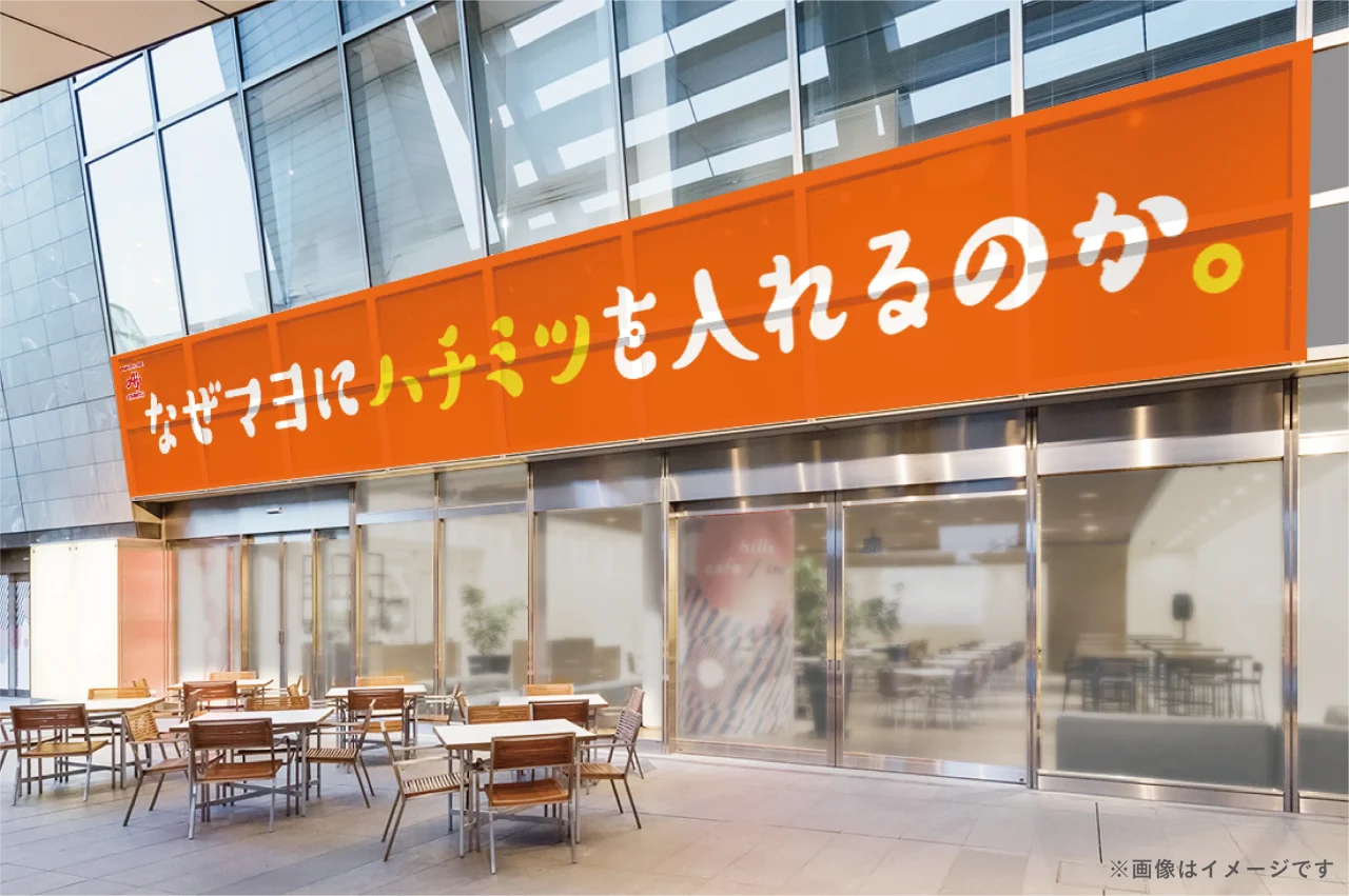 建物外壁に掲げた『なぜマヨにハチミツを入れるのか。』のオレンジ色の看板