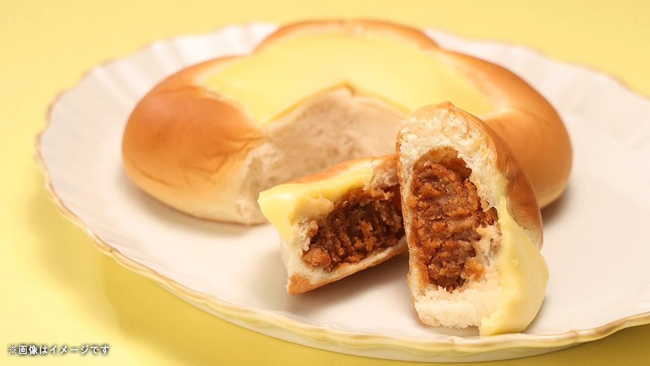 マヨのせちゃったメンチカツぱん。皿にのせ、割った断面に具と黄色いソースが見える