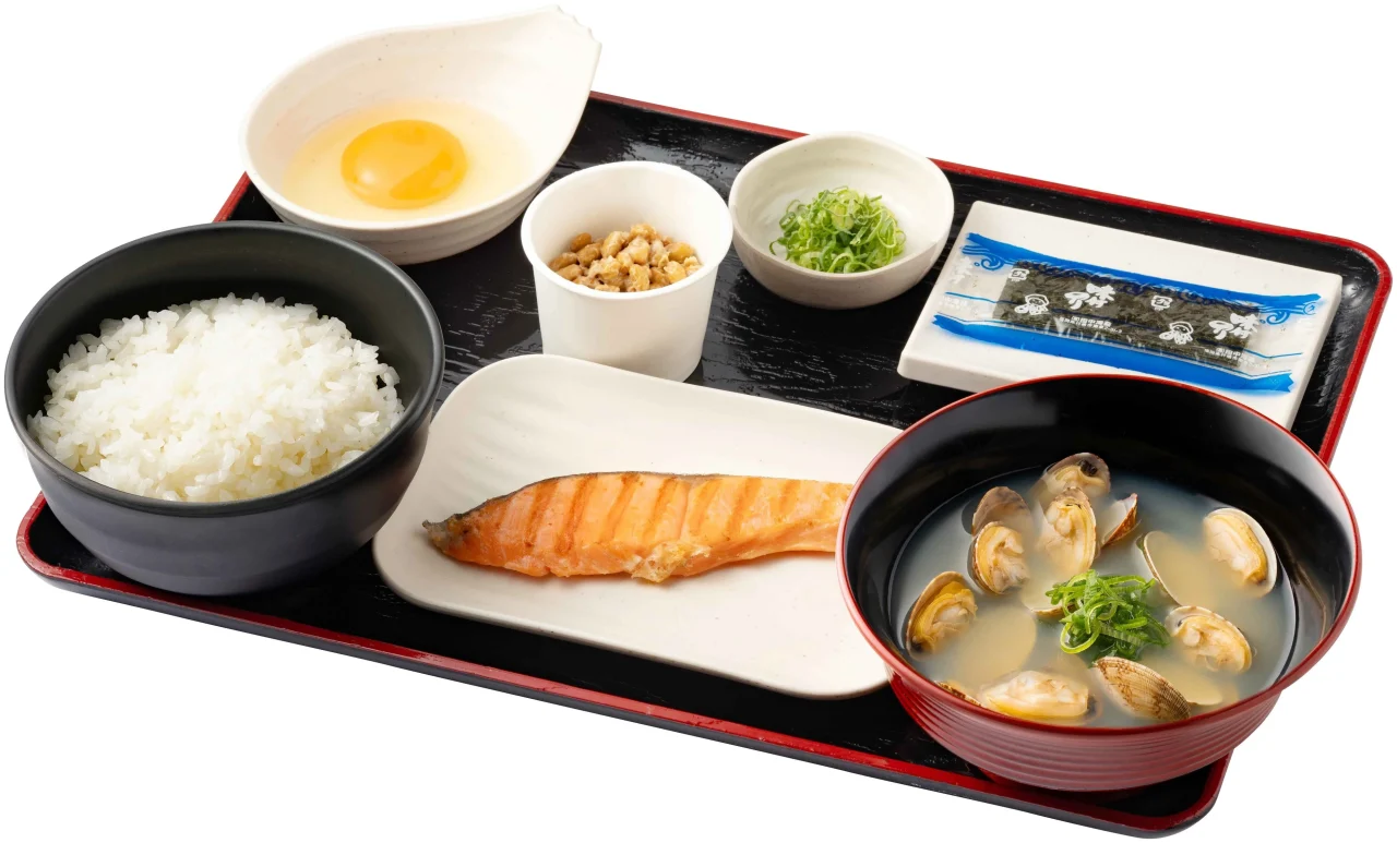 鮭納豆貝汁定食。焼鮭・納豆・生たまご・ご飯・味付けのり・貝汁をお盆に並べた様子