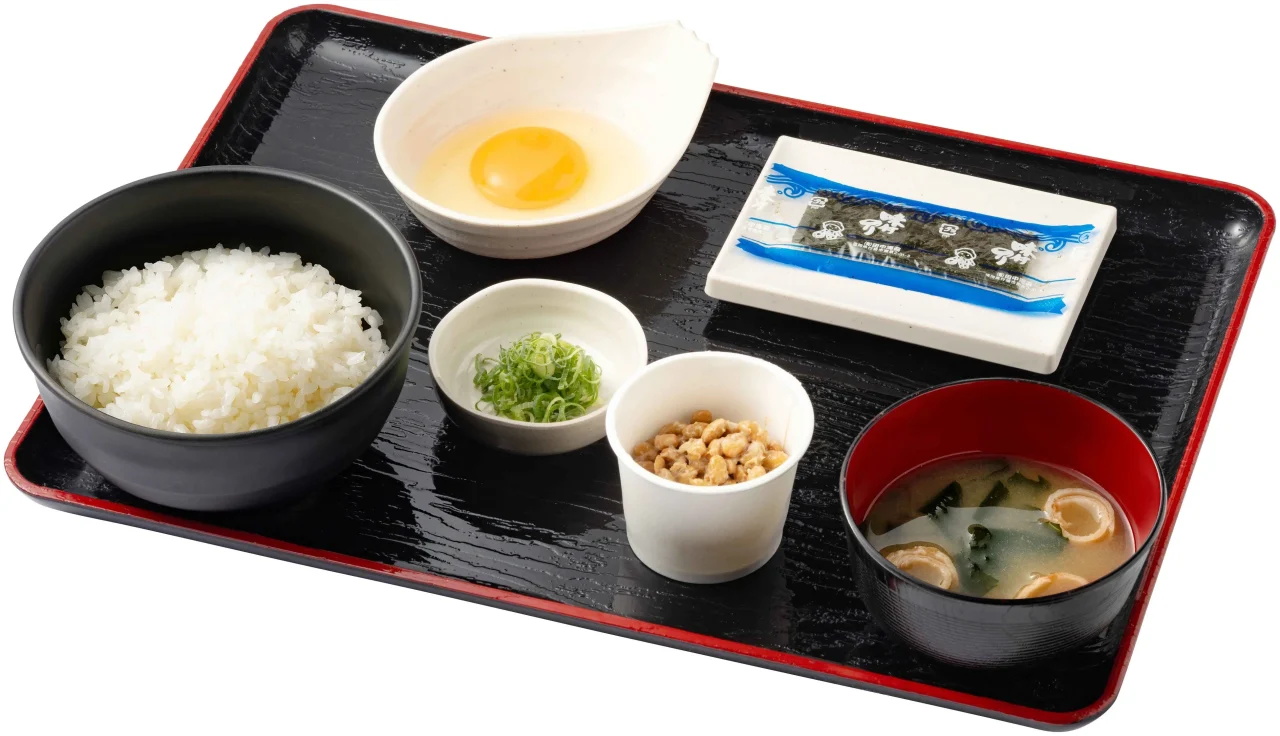 納豆定食。ご飯、生たまご、味付けのり、納豆、薬味、みそ汁を黒いお盆にのせた朝定食